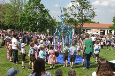 Kinder tanzen um den Maibaum